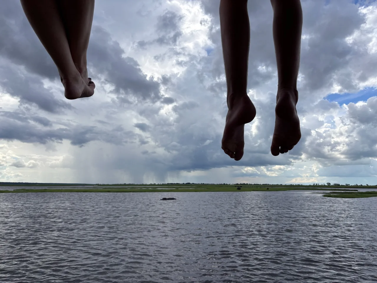Les pieds des passagers au-dessus du Chobe pendant une sortie en bateau.