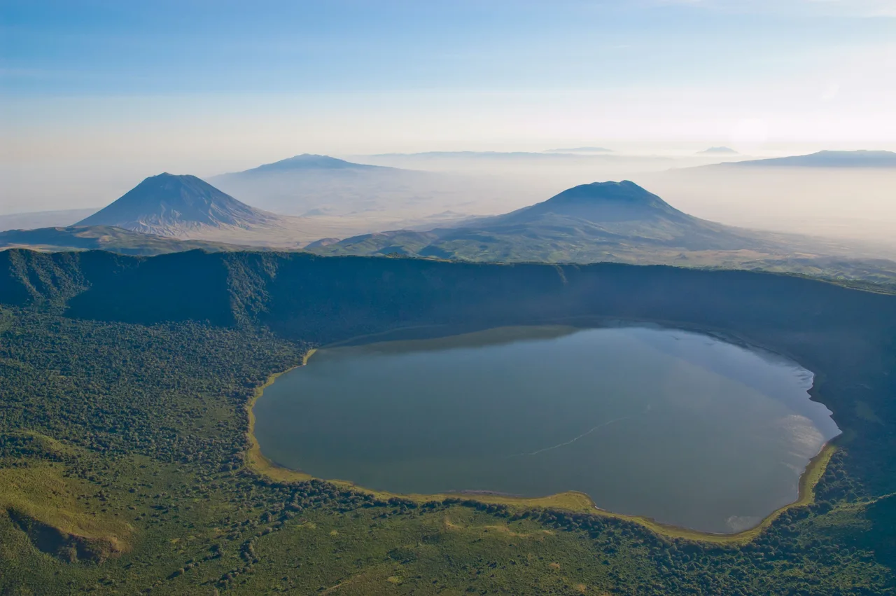 Le lac du cratère d’Empakaai entouré de ses versants boisés.