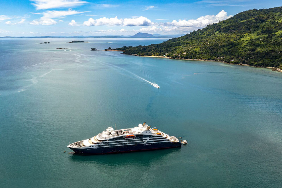 Un yacht est amarré dans une baie turquoise près d’une côte verdoyante à Madagascar.