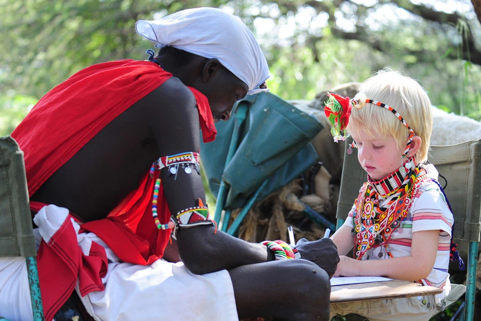 Un moment de partage entre un guide maasaï et un jeune voyageur lors d'une découverte culturelle en Afrique de l'Est.