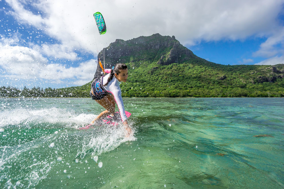 Une femme fait du kitesurf sur une eau turquoise à l'île Maurice.
