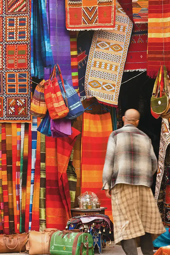 Étals de tapis et textiles colorés dans un souk marocain traditionnel.