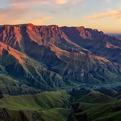 Lumière dorée sur les reliefs du Drakensberg en Afrique du Sud, symbole de la beauté naturelle et de la diversité du pays.