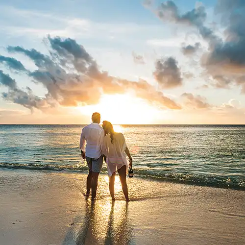 Couple marchant main dans la main au bord de la mer au coucher du soleil, voyage romantique en Afrique
