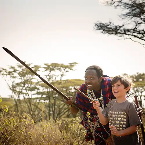 Jeune garçon et guide massaï observant la savane pendant un safari en famille en Afrique