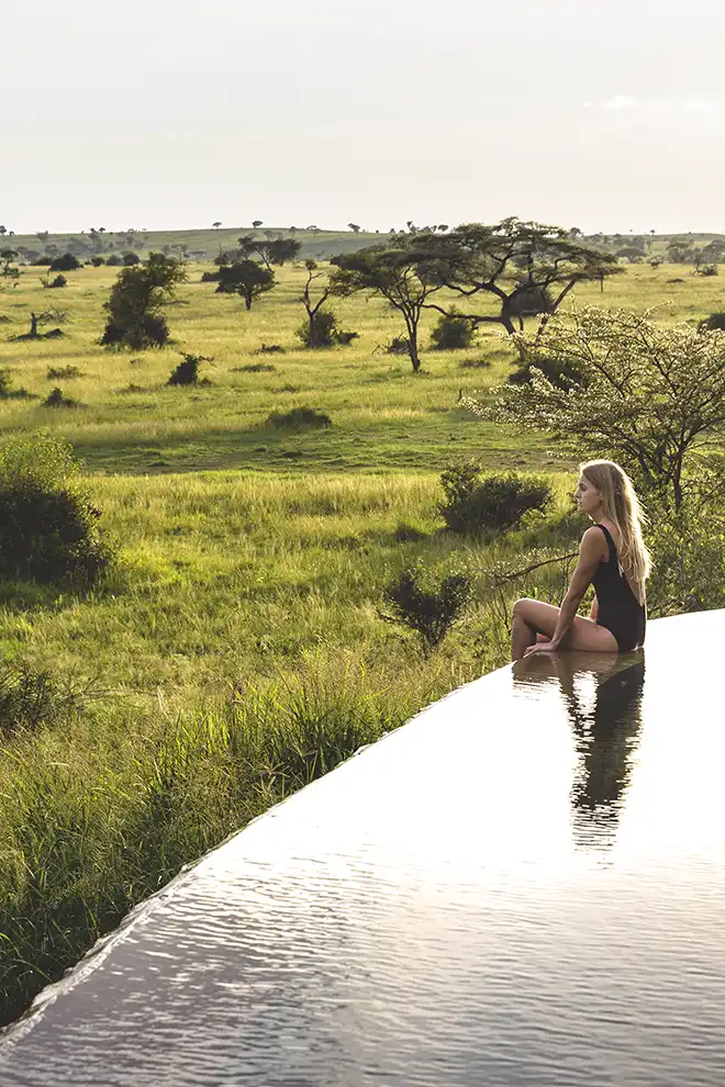 Voyageuse profitant d’une piscine privée avec vue sur la savane africaine.