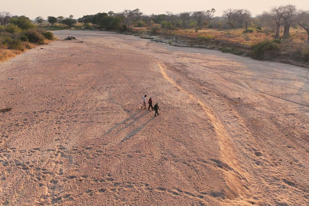 Vue aérienne de trois personnes marchant dans le lit asséché d’une rivière en Tanzanie.